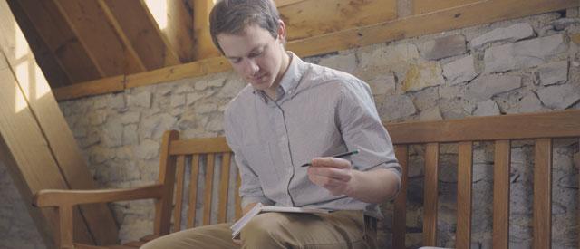 a 威尼斯游戏大厅 student sitting 和 writing on a notepad.